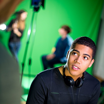 students work on a shoot with a green screen behind them