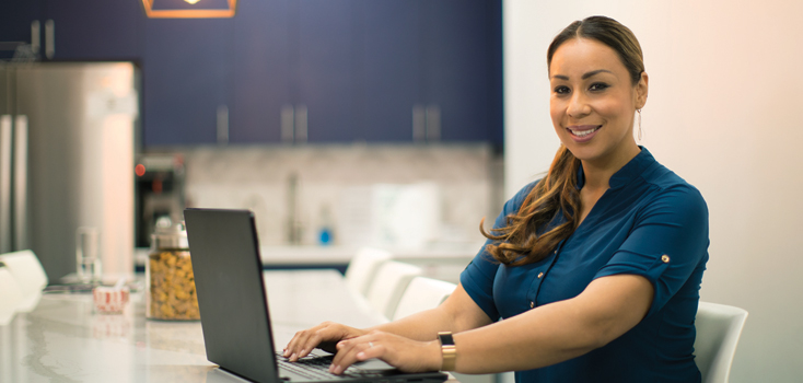 a woman works on a laptop at home