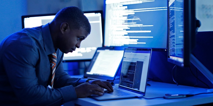 man on a computer with dramatic blue lighting on him