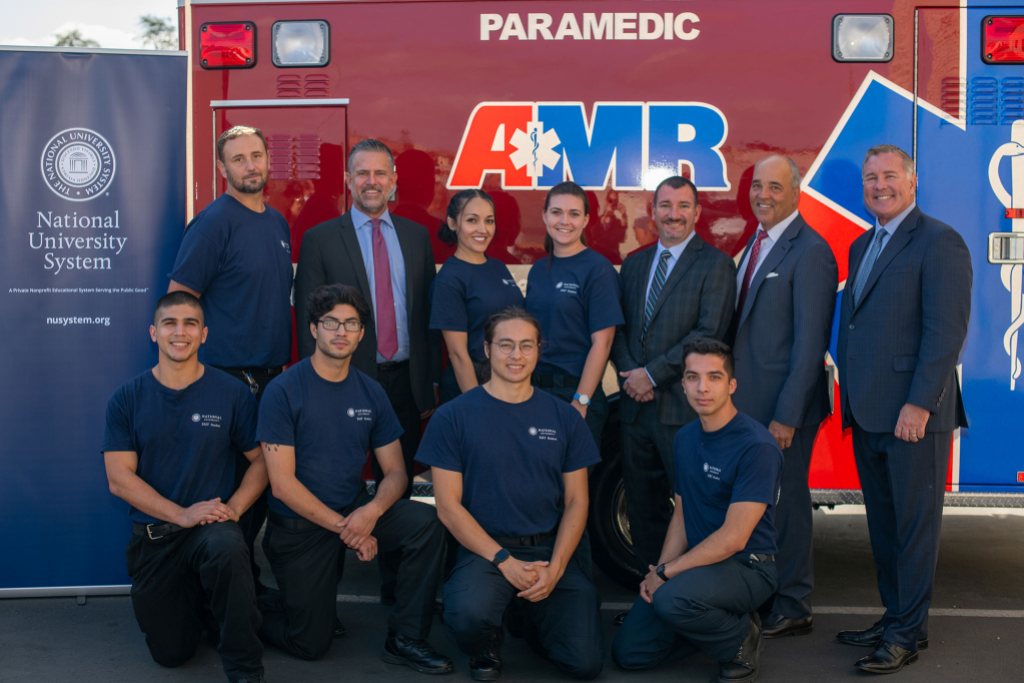 AMR employees and members from NU pose in front of an AMR ambulance