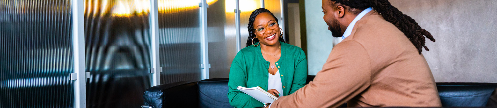 Brittneii P. smiles at a colleague in a conference room.