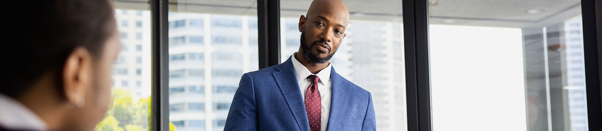 Teddy T., Class of 2021, stands in front of a glass door in a blue suit with a red tie