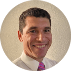 Headshot of Dr. Brian Tilley, PhD, MA in Counseling Associate Professor & Program Director, a clean-shaven man in a white shirt and printed tie.