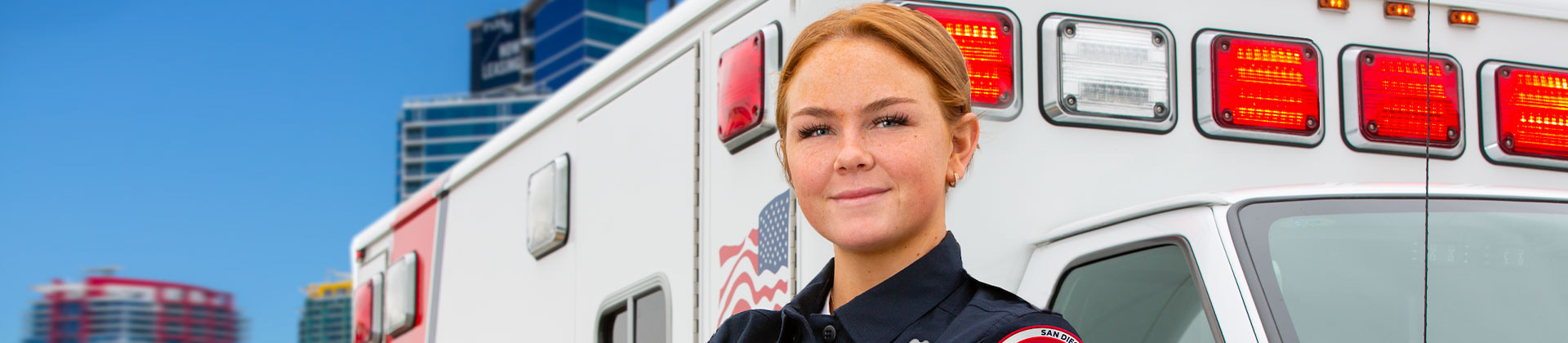 woman in uniform stands in front of an ambulance