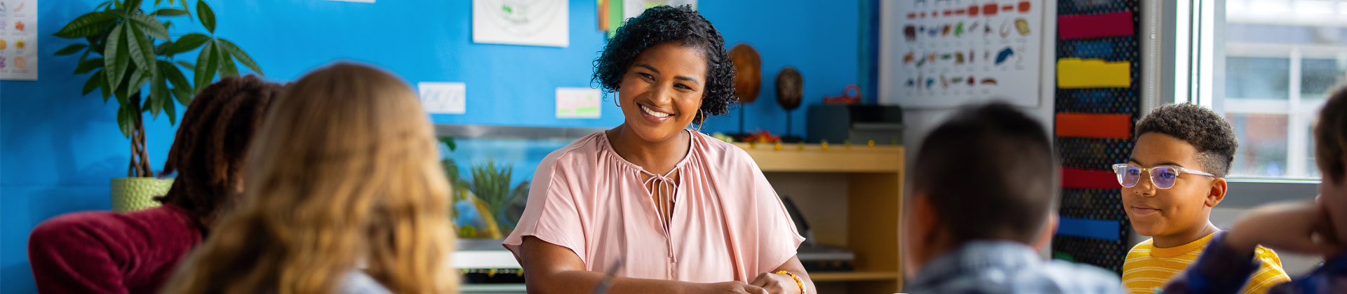 Teacher smiling in classroom with children around her