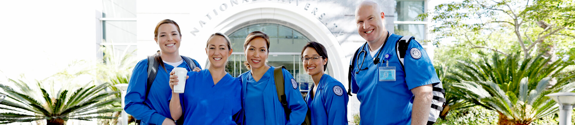 Five National University Nursing students post in front of the NU building.