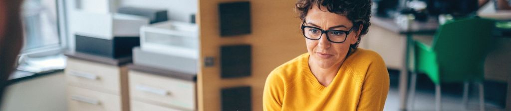 woman in office wearing glasses and looking down with concentration