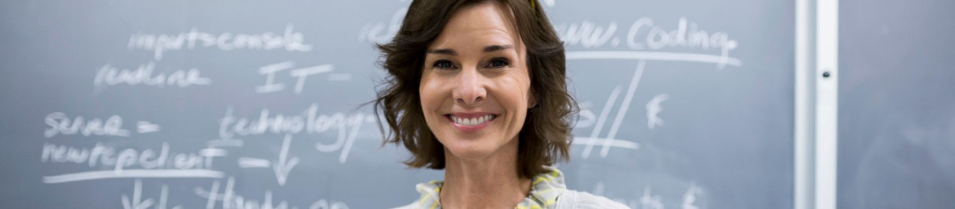 woman smiling into camera with chalkboard behind her