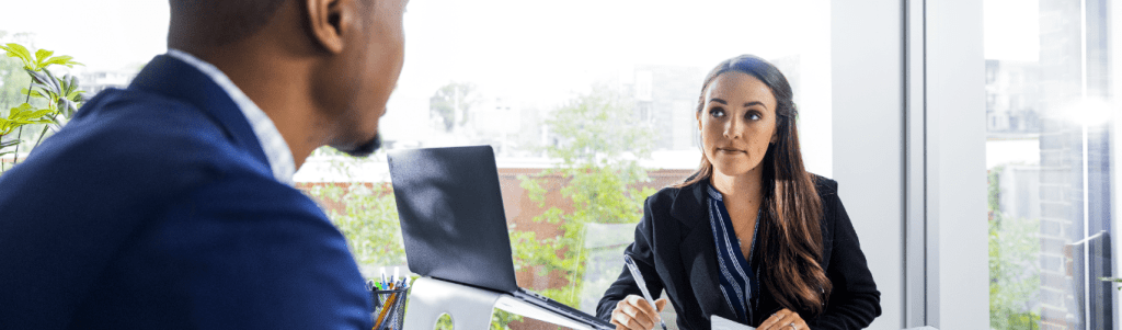 two business professionals sitting at a desk discussing a business administration degree