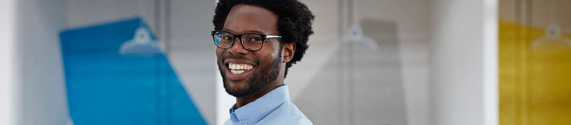 man with glasses and a beard smiling in office 