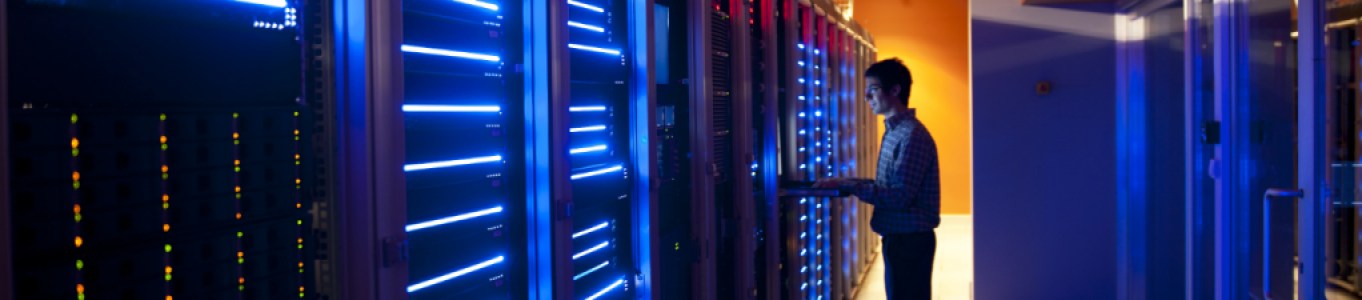 man standing in server room looking at server rack