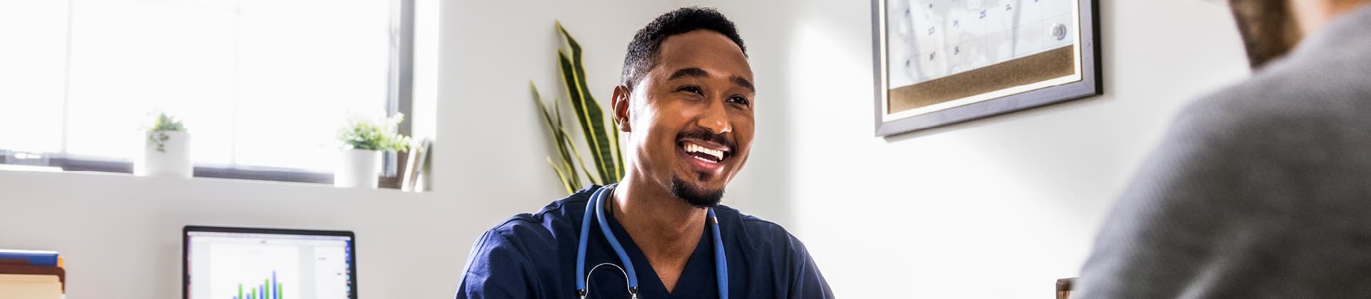 medical professional man smiling at patient sitting across from him at desk