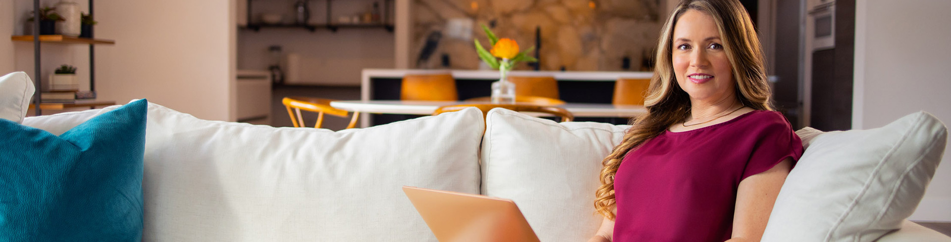 woman sits on a couch with a laptop