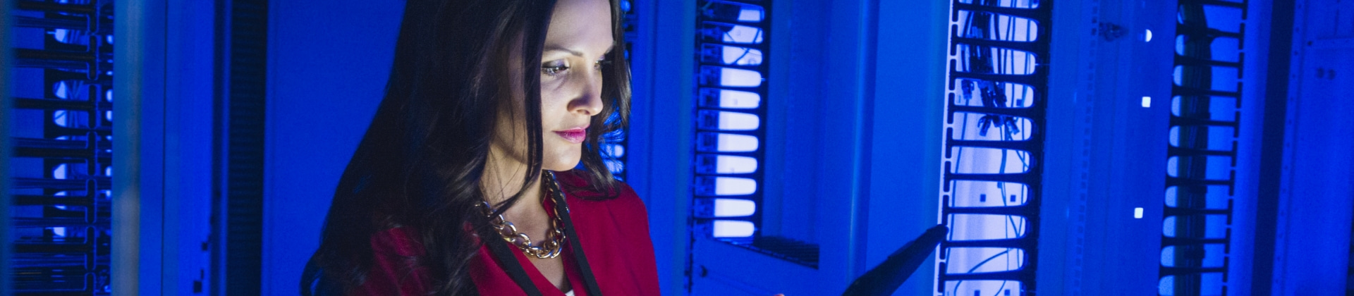 woman in a server room looks at a tablet