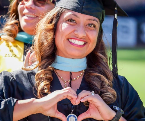 graduate smiles and makes heart shape with her hands