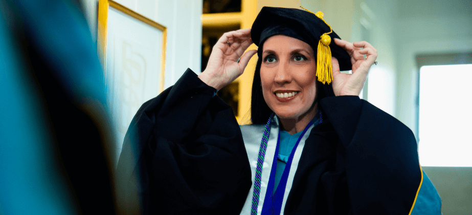 Person wearing cap and gown looking in the mirror