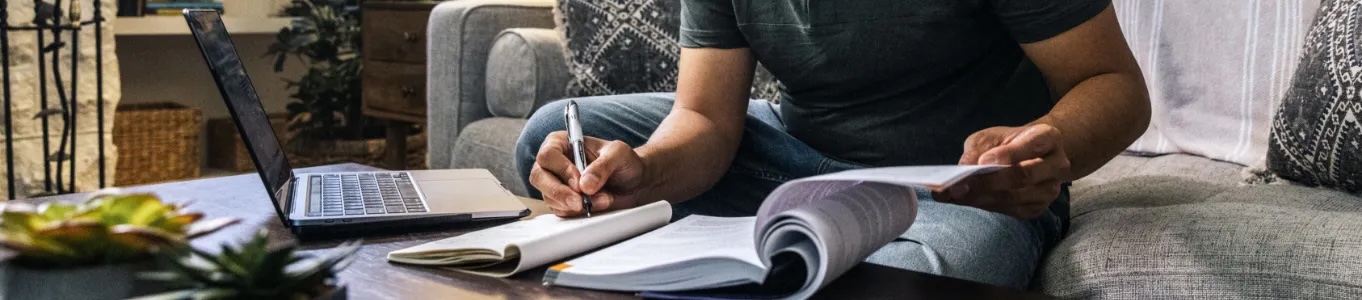 person sitting on sofa working on school work at coffee table